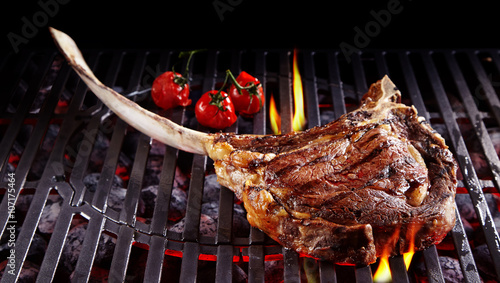 Single tomahawk rib steak on hot grill photo