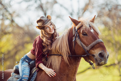 Beautiful smiling girl riding horse on autumn field