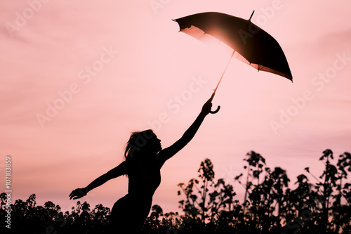 Abgekoppelte Frau in Silhouette mit Schirm fliegt in die Zukunft. Warme Szene mit fliegendem M  dchen. Zeigt die Vorstellungskraft und den Aufbruch zu neuen Horizonten wie Klimawechsel oder Achtsamkeit