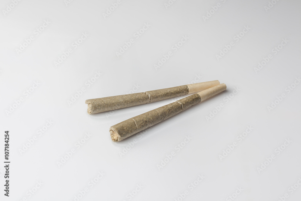 Two medical cannabis rolled joints on light background from side high angle Two medical cannabis rolled joints on light background from side high angle