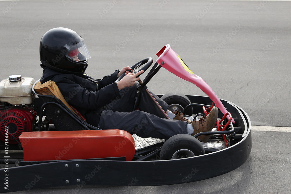 boy is driving Go-kart car with speed in a playground racing track.