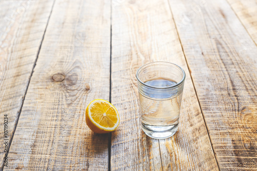 glass of fresh water with half lemon on wooden table