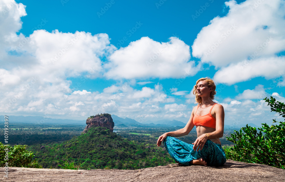 Young woman meditation on the mountain Pidurangala Rock, Sri Lanka. Sigiriya