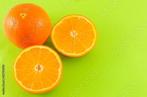 Whole and sliced orange on green background