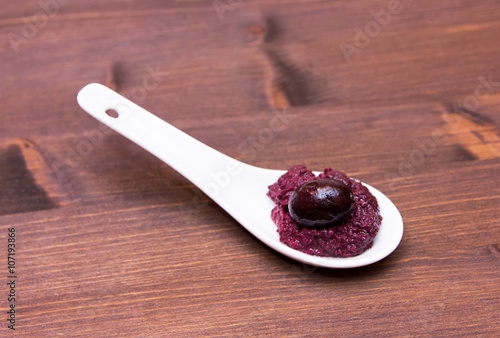 Olive paste on spoon on wooden table