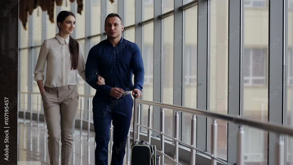 Happy loving couple in casual wear walking with a luggage by airport terminal. Happy loving couple in casual wear walking with a luggage by airport terminal.