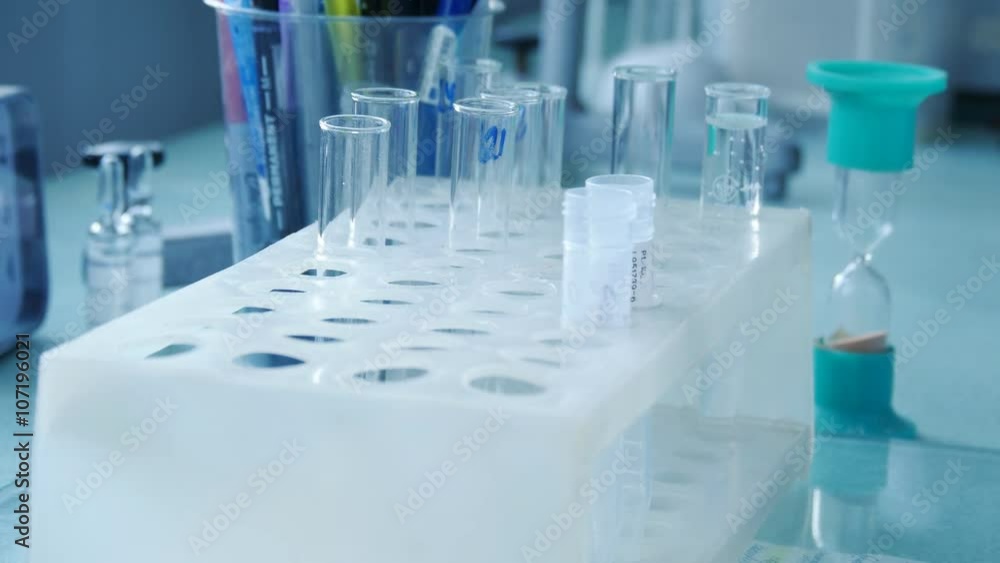 Hand of doctor putting test tube and turning the hourglass. Hand of doctor putting test tube and turning the hourglass.