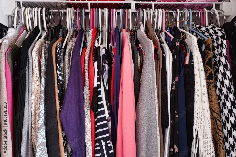 Crowded closet of colorful women's clothing on hangers