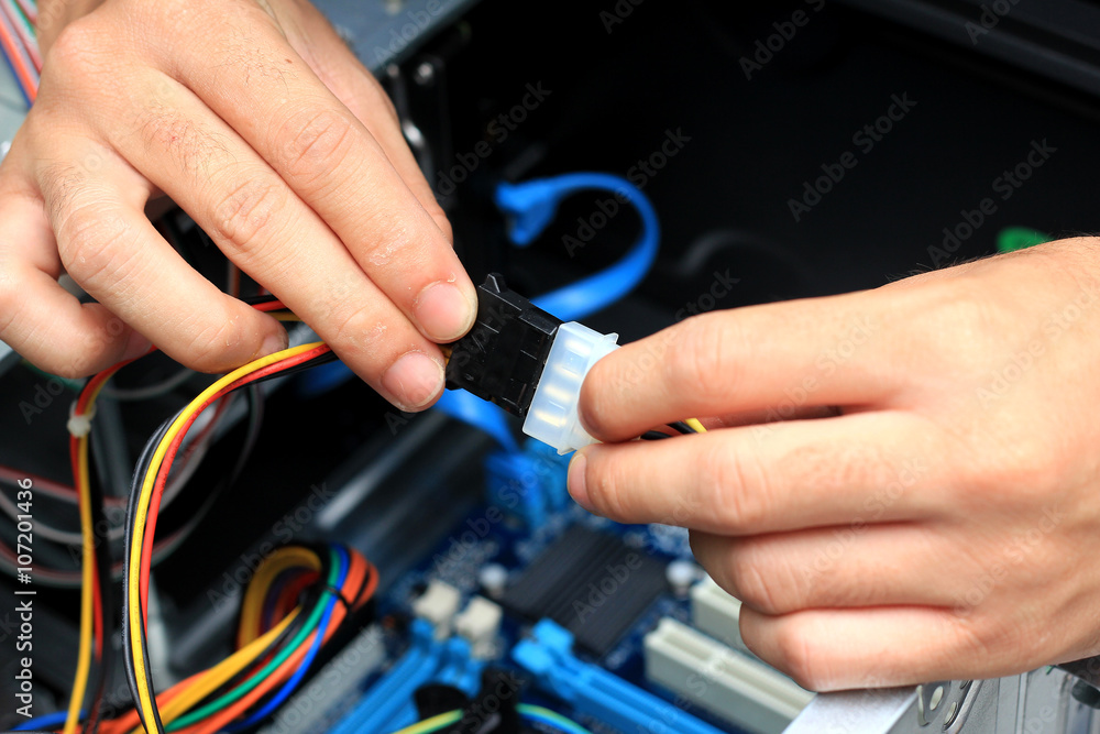 Closeup of a technician's hands wiring a computer mainboard