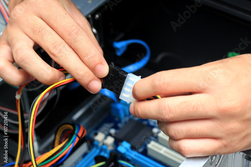 Closeup of a technician's hands wiring a computer mainboard