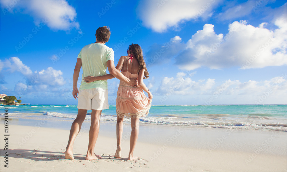 back view of couple in bright clothes having fun at tropical beach back view of couple in bright clothes having fun at tropical beach