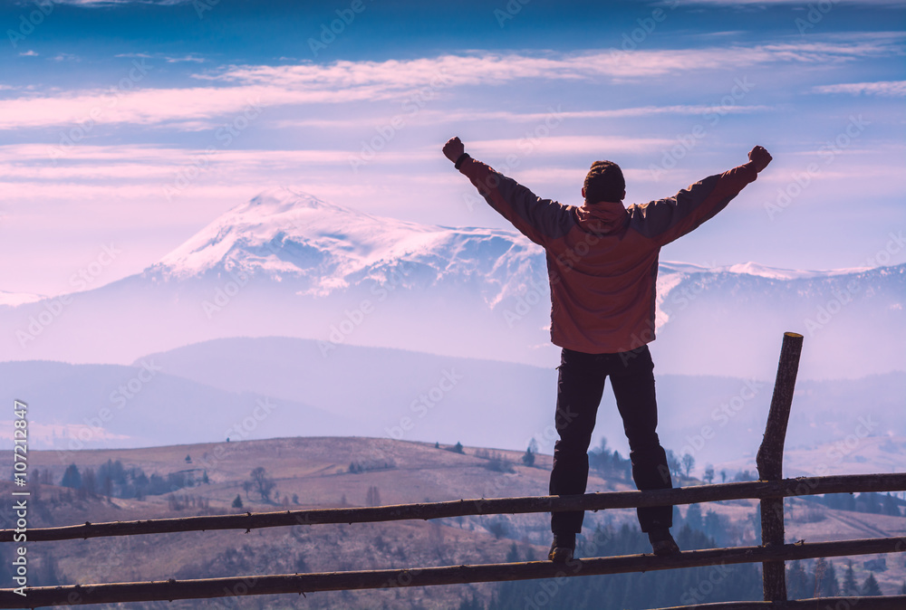 A hiker on a fence with raised hand A hiker on a fence with raised hand