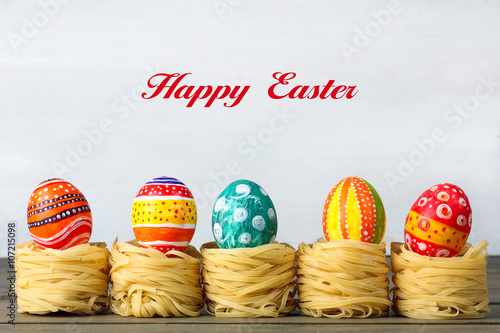 Easter eggs, painted in different colors and lies on Italian pasta on wooden background with inscription