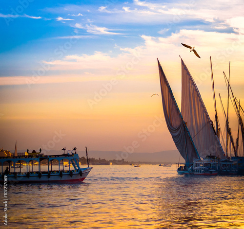 Feluccas at sunset - traditional sail vessel on Nile river in Egypt. photo