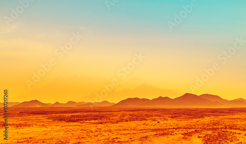 African landscape, hot climate in stone desert with silhouettes of hills on the horizon.