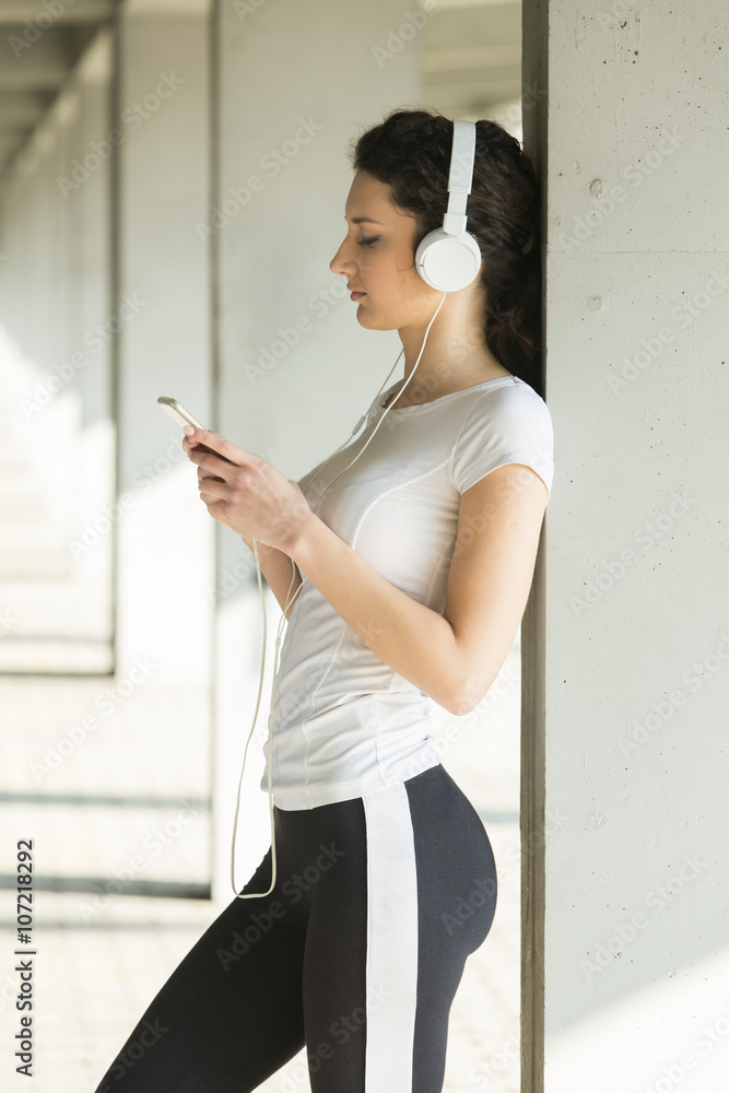Fitness girl listening to music between workouts