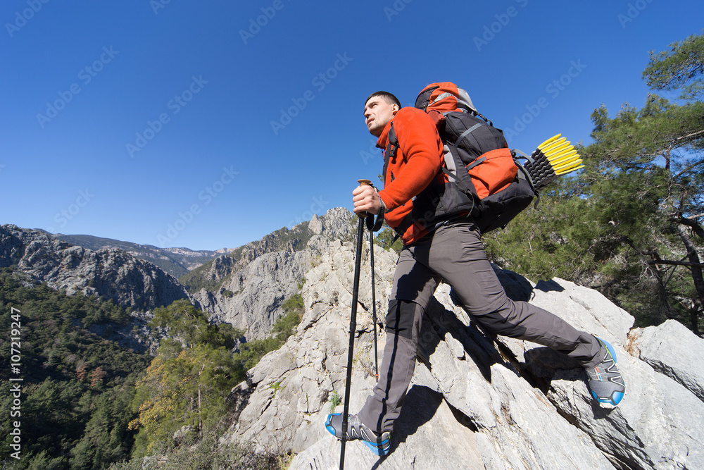 Young man with backpack on a mountain top on a sunny day. 