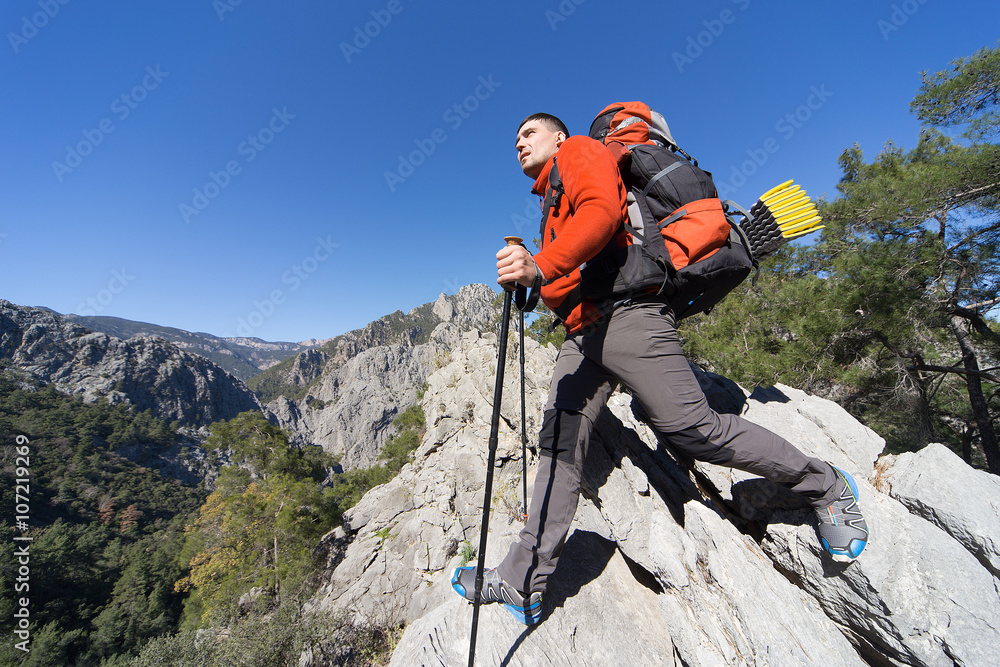 Young man with backpack on a mountain top on a sunny day. 