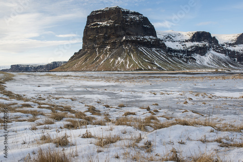 Landscape with snow covered grass and Lomagnupur mountain, Iceland photo