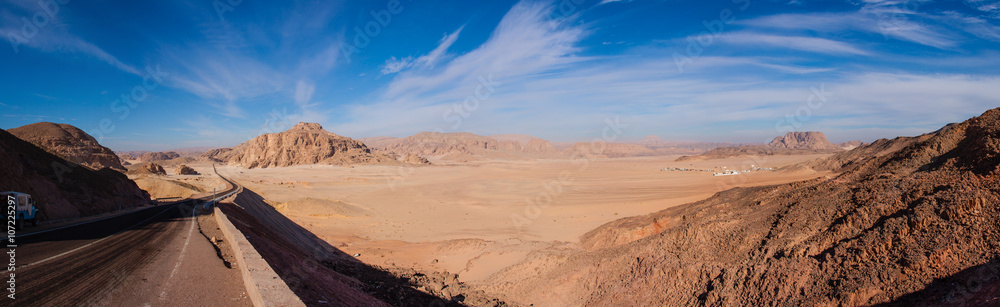 Panorama of the desert in Egypt and the road stretches to the horizon, against the clear sky