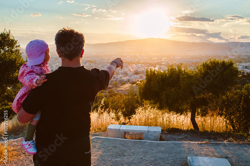 father holding his baby looking to the sunset