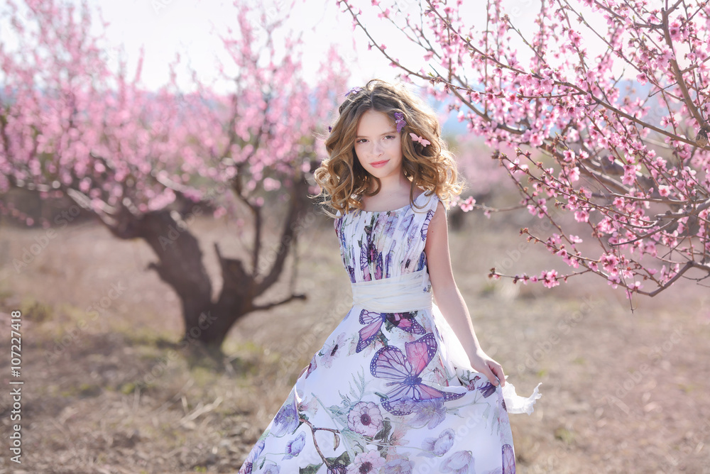 Young  girl on a background of a flowering peach tree