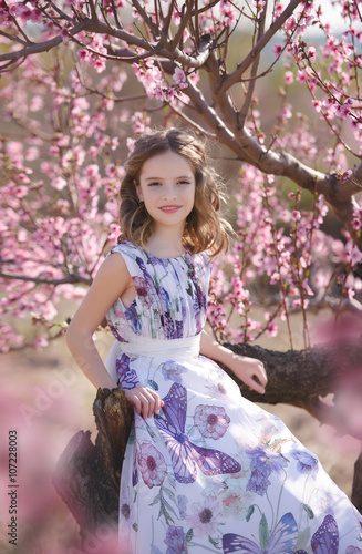 Young girl against pink tree in blossoom photo