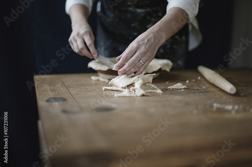 A woman using raw pastry dough to line a pie dish and finish the edge.