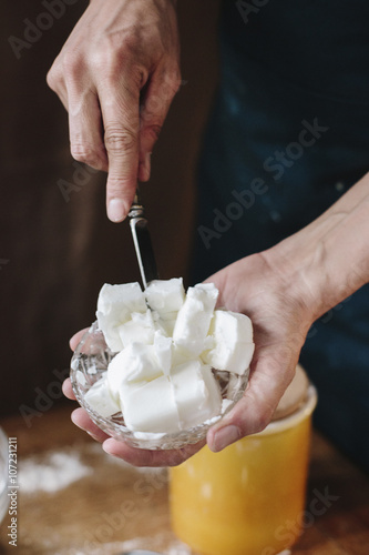 A person using a knife to dice lard for cooking. 