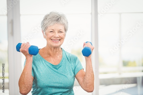 Portrait of smiling senior woman holding dumbbell