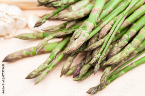 Fresh asparagus stems and garlic on a wooden board