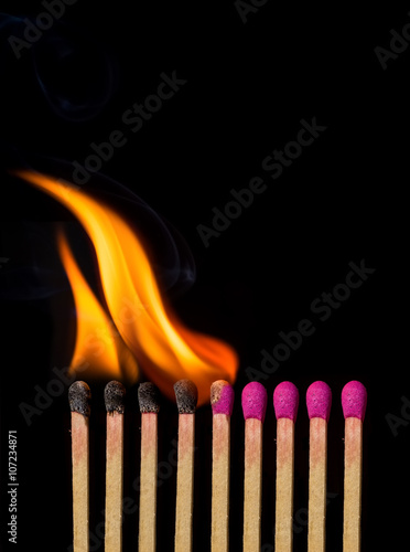 Line of lighted matches on black background