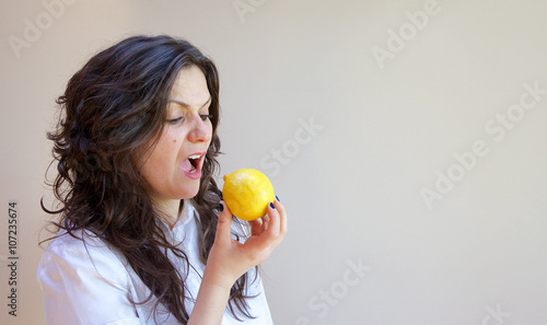 A young a lady bites a lemon photo