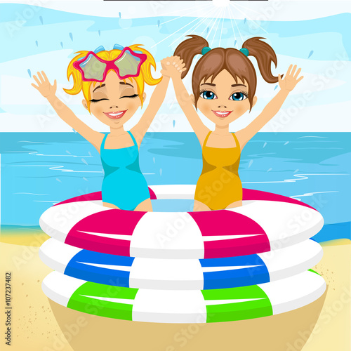 cute little brother and sister swimming in inflatable pool at the beach