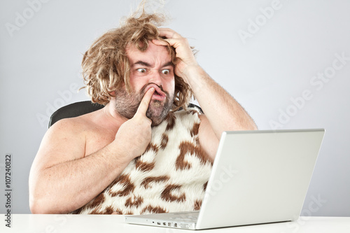 ugly doubtful prehistoric man on laptop