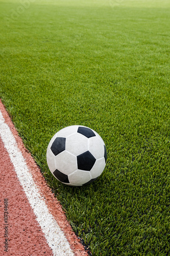 The football is on the artificial grass soccer field in the stadium.