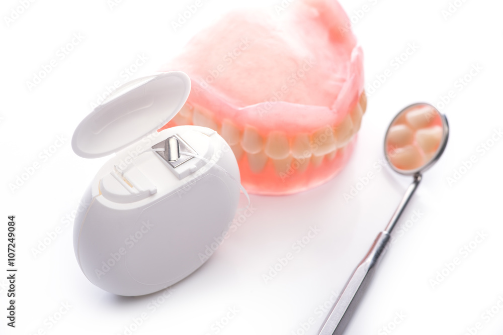 Teeth model with dental floss and mouth mirror on white background Teeth model with dental floss and mouth mirror on white background