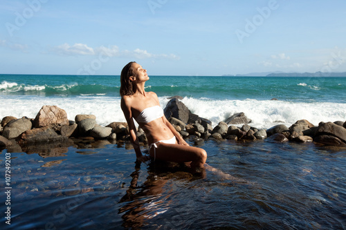 belle femme assise dans l'eau au bord de la mer dans des rochers 