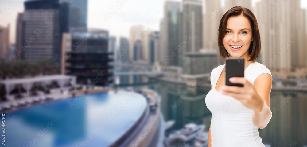 woman taking picture by smartphone over dubai city