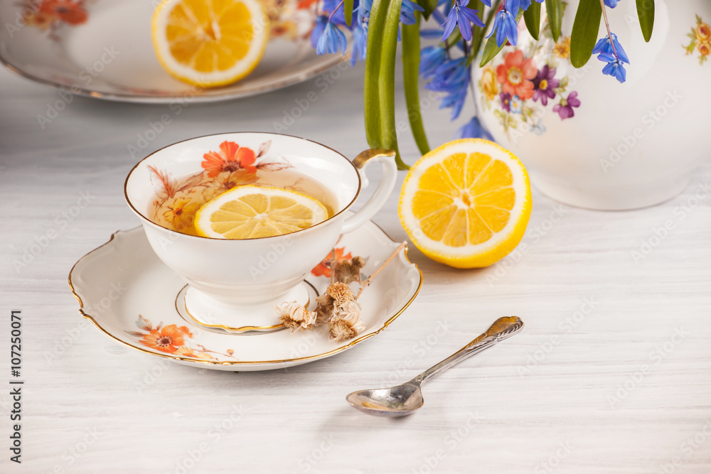 Tea with lemon and bouquet of blue primroses on the table Tea with lemon and bouquet of blue primroses on the table