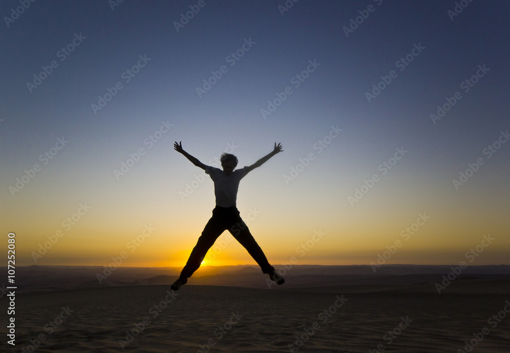 jumping man with hands up at sunset in desert