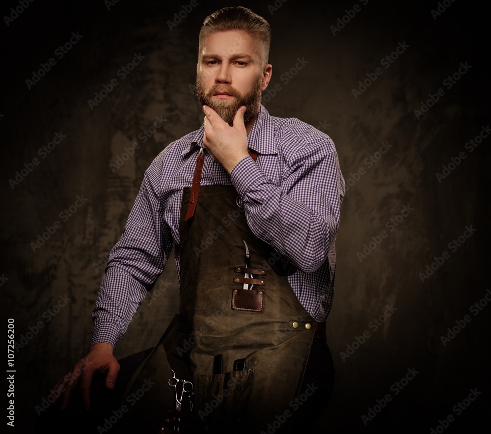 Portrait of stylish barber with beard and professional tools isolated on a dark background. Portrait of stylish barber with beard and professional tools isolated on a dark background.