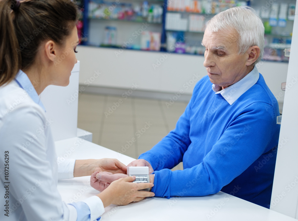 Fototapeta premium Beautiful young woman pharmacist measuring blood pressure to sen