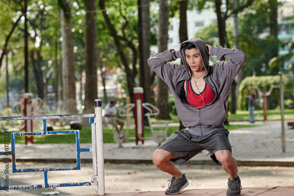 Vietnamese fit man doing squats in the park