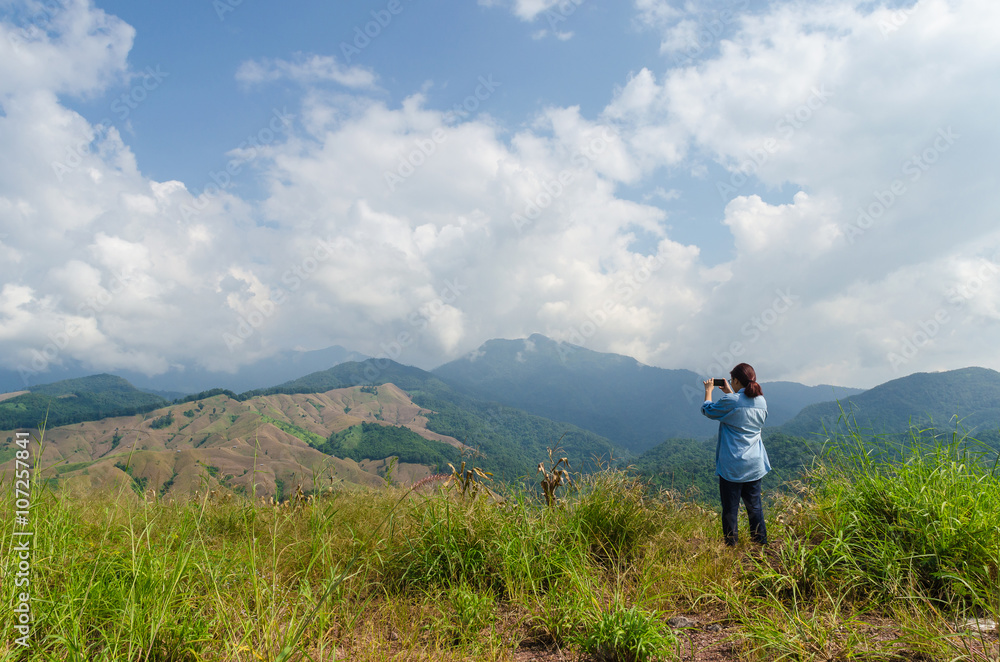 Female traveler with smart phone taking a photo of beautiful landscape at nan thailand