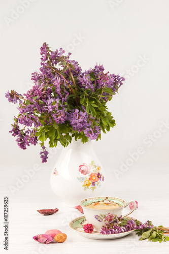 Tea with  lemon and bouquet of  lilac primroses on the table