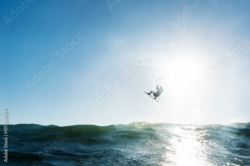 Surfer jumping in front of the sun