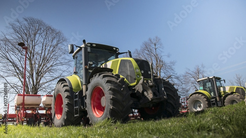 Green tractors in the field with a blue sky