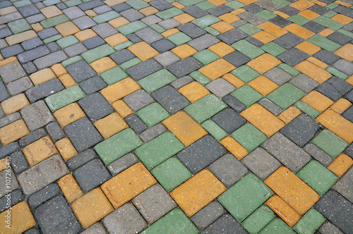Pavement rectangular tiles of yellow  gray and green color.