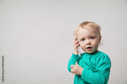 Cute little baby is talking on cell phone, isolated over white